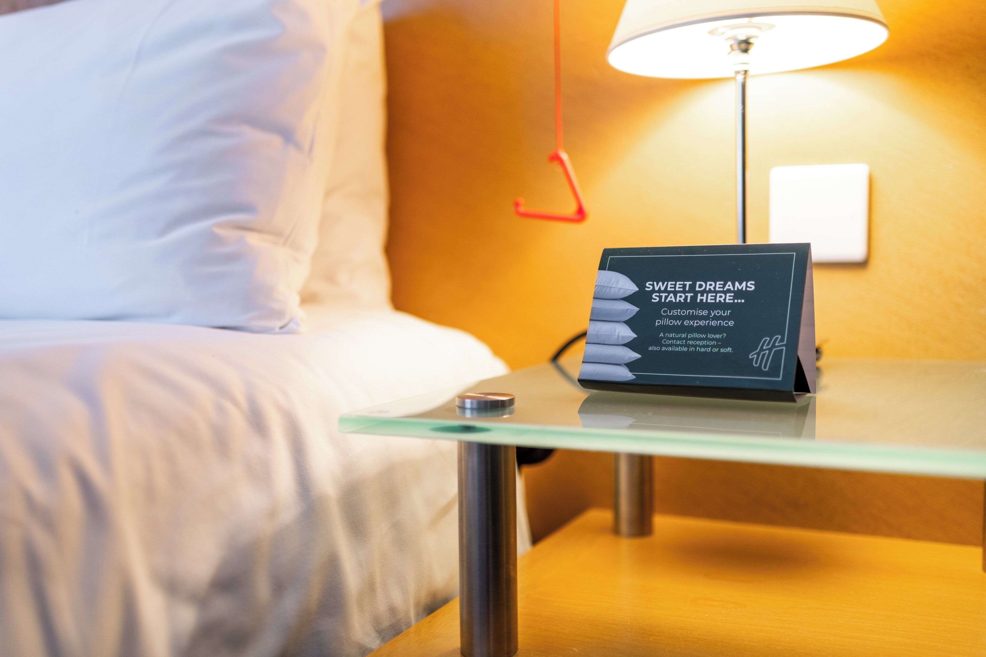 Ein Hotelzimmer mit einem Bett, einem Glastisch mit einem Schild und einer Lampe.