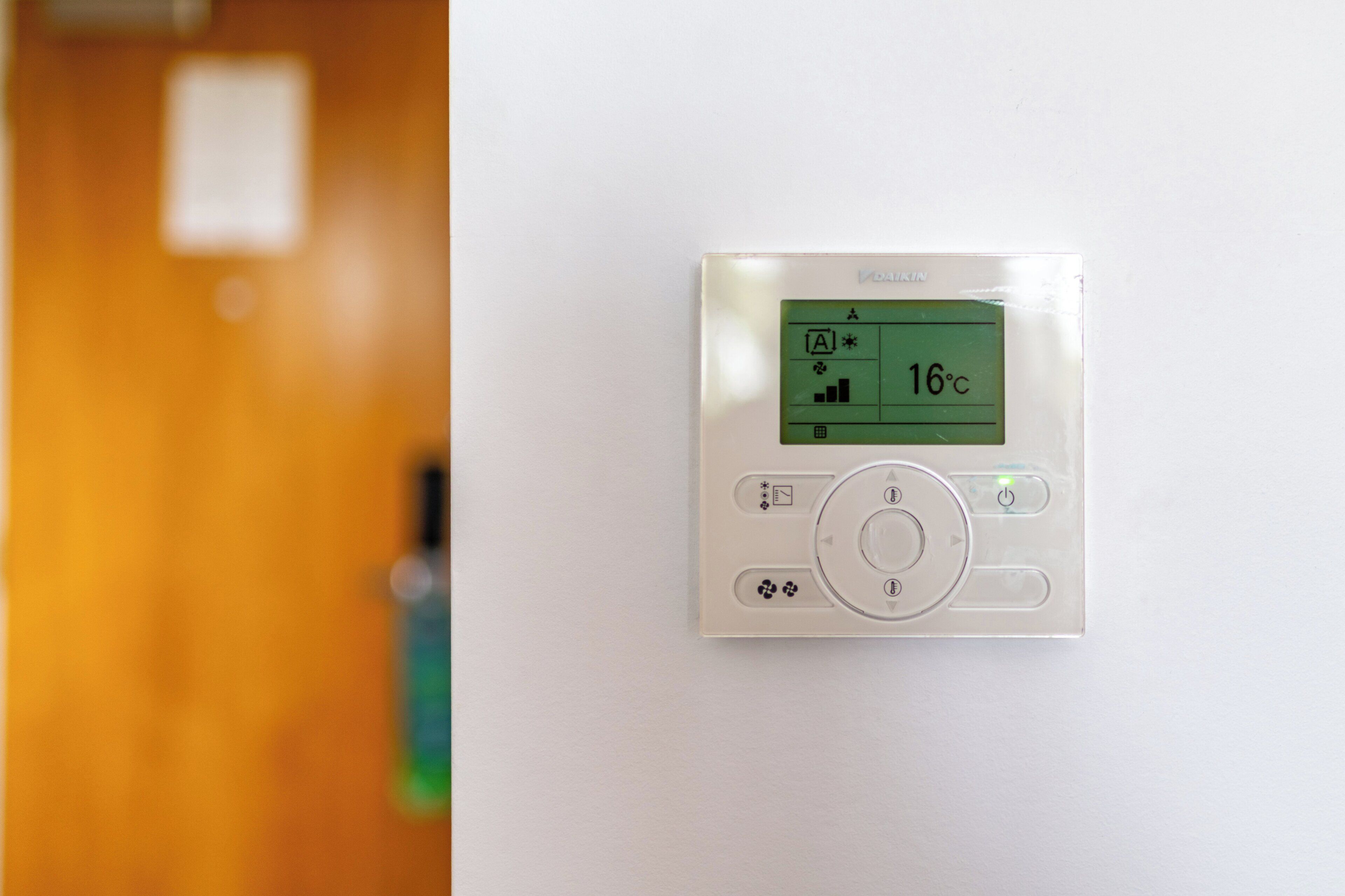 Un thermostat fixé au mur, doté d’un écran numérique indiquant une température de 16 degrés Celsius.