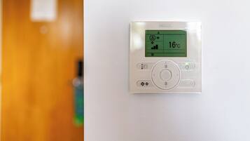 Un thermostat fixé au mur, doté d’un écran numérique indiquant une température de 16 degrés Celsius.