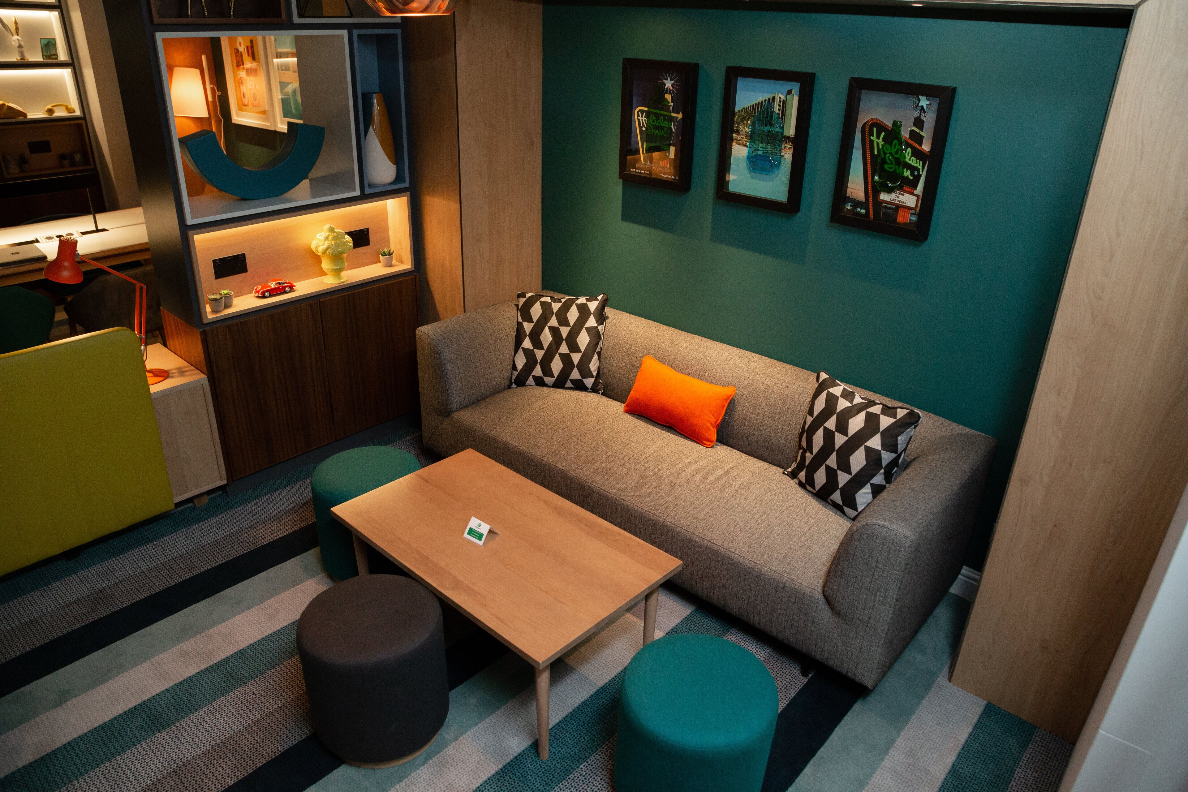 Una sala de estar moderna con un sofá, otomanas, una mesa de centro y una cocina con mostrador y estanterías.