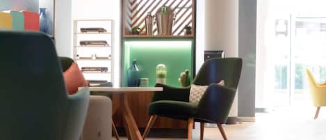 A modern interior with a green accent wall, a wooden table, and a variety of chairs.