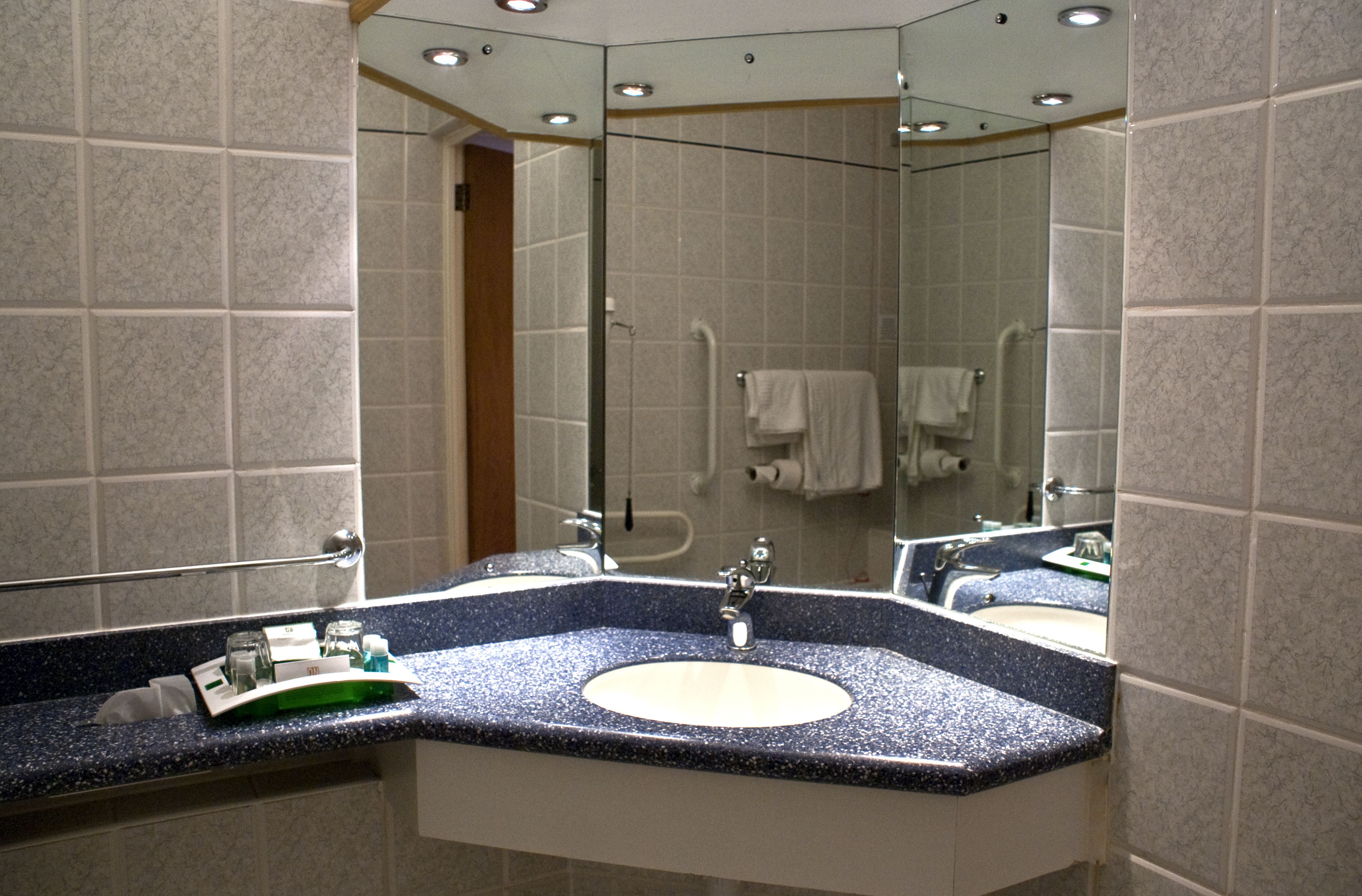 A modern bathroom with two sinks, a glass shower enclosure, and a large mirror.
