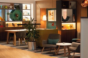 A modern interior with a dining area, seating, and a plant. - Holiday Inn Ashford North A20 by IHG (Ashford)