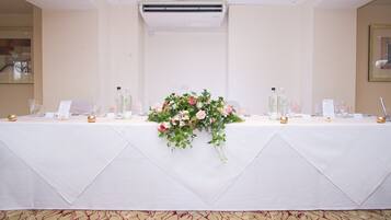 A banquet table set with a floral centerpiece, two bottles of water, and a menu sign.