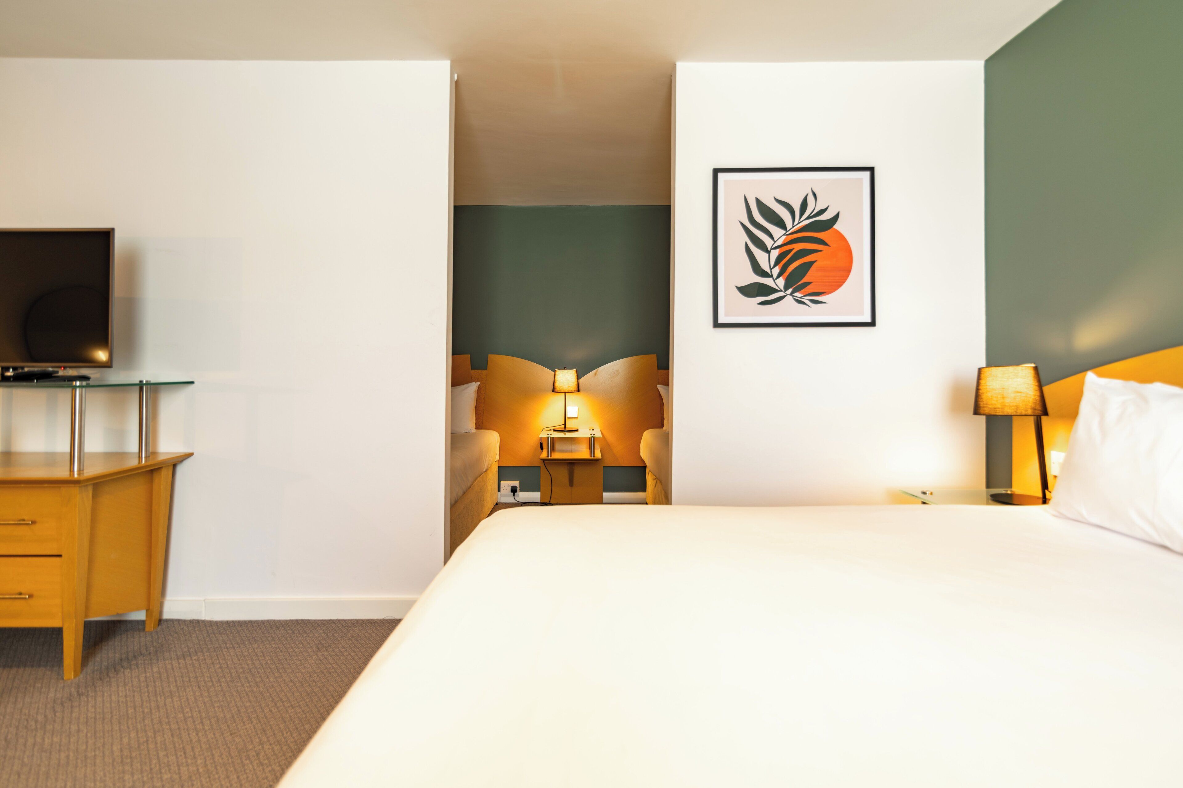 Hotellihuone, jossa on sänky, televisio, työpöytä ja tuoli.