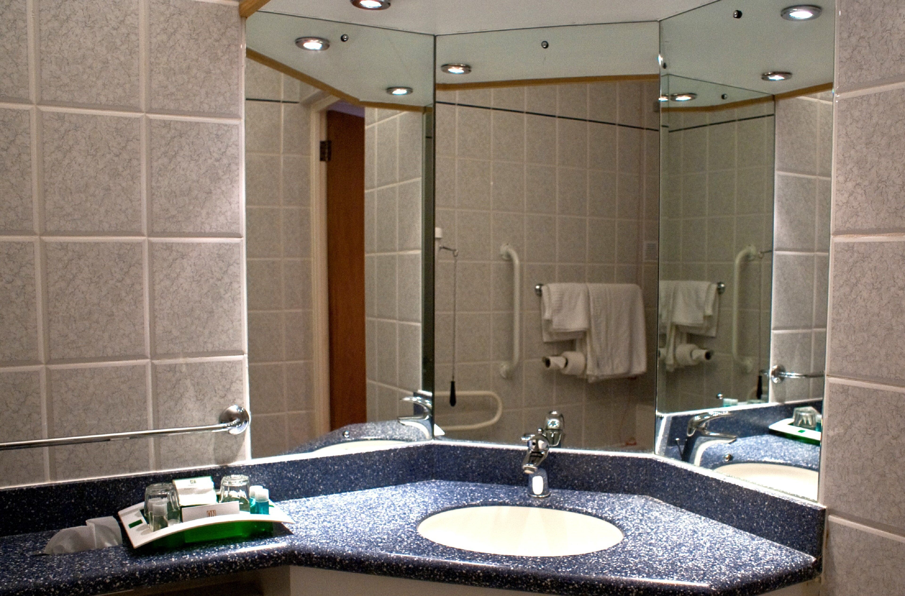 Un baño con un espejo grande, un lavamanos y una zona de ducha.