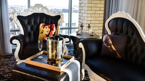 A luxurious room with a black leather sofa, a cushioned armchair, and a tray table with a champagne bottle and glasses. - Lorenzo Hotel Dallas, Tapestry Collection by Hilton (Dallas)