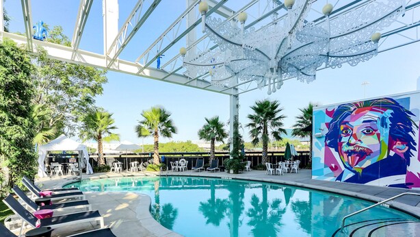 A pool area with lounge chairs, a tent, and a mural. - Lorenzo Hotel Dallas, Tapestry Collection by Hilton (Dallas)