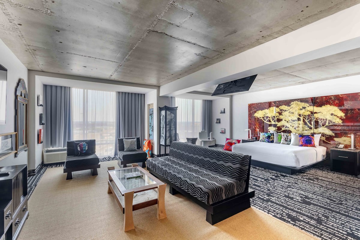 Moderni hotellihuone, jossa on suuri sänky, sohva, sohvapöytä ja televisio.