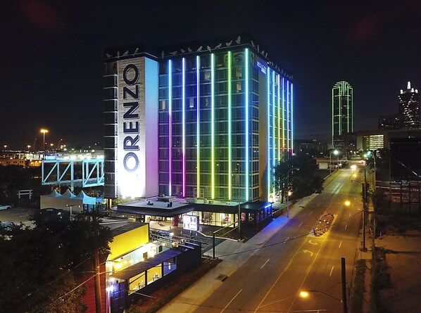 Un hôtel reconnaissable à son grand panneau « ORENZO », doté d’une architecture moderne avec des bandes lumineuses verticales.