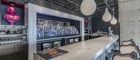 A bar area with a marble countertop, shelves with bottles, and a neon bust.