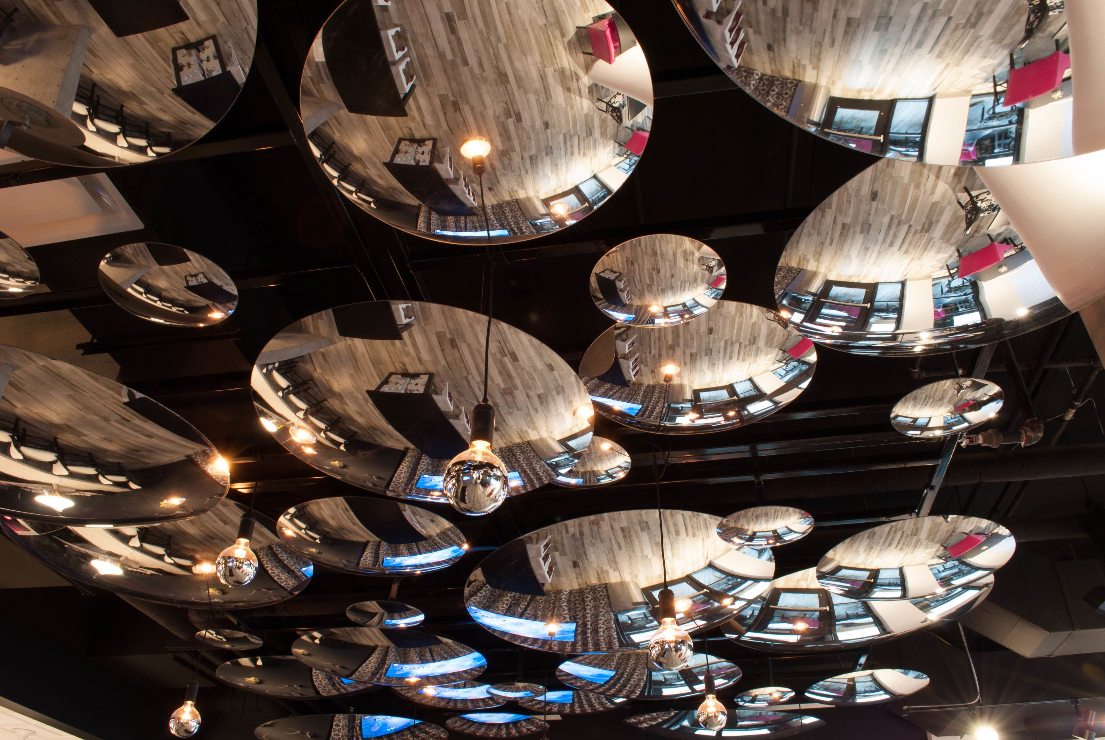 A ceiling with multiple circular mirrors reflecting the interior of a modern building.