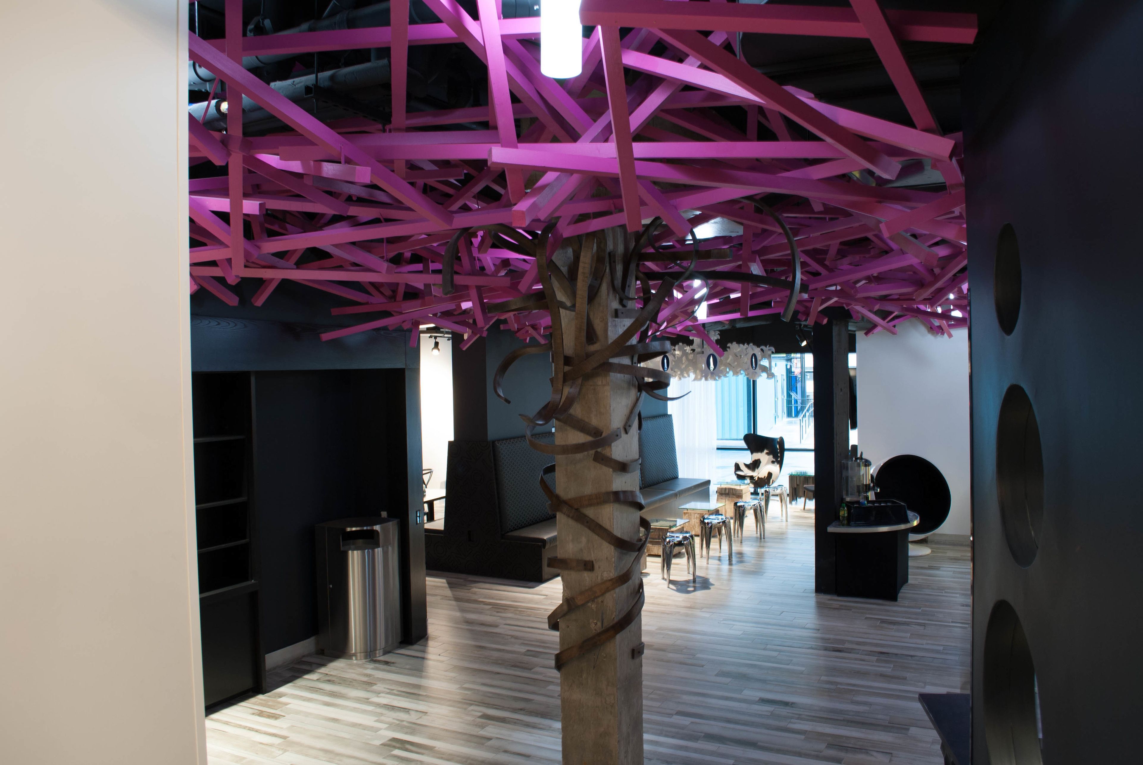 A modern interior with a wooden sculpture, seating areas, and a wooden floor.