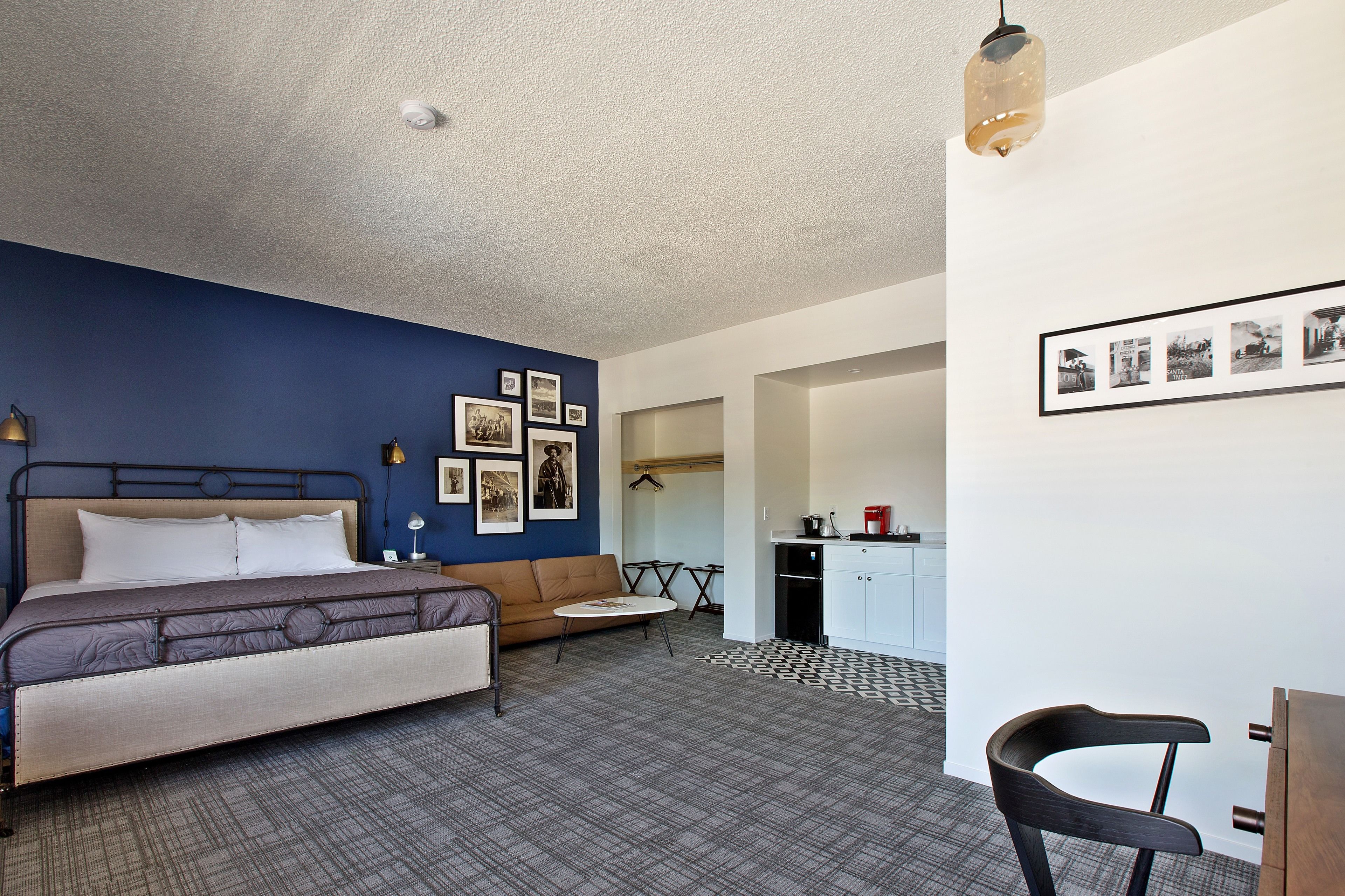 A bedroom with a bed, a sofa, a dining table, and a chair.