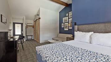 Ein Hotelzimmer mit einem Bett, einem Schreibtisch, einem Stuhl, einem kleinen Tisch und einem Kleiderschrank.