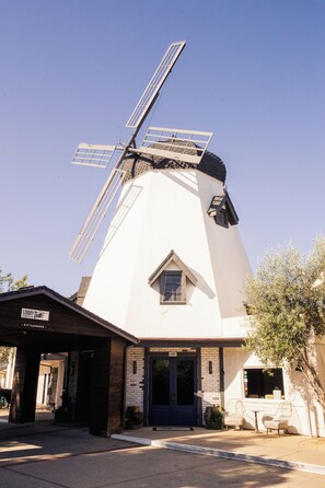 A windmill with a white facade and a blue door, adjacent to a building with a sign reading "Lobby Check In."