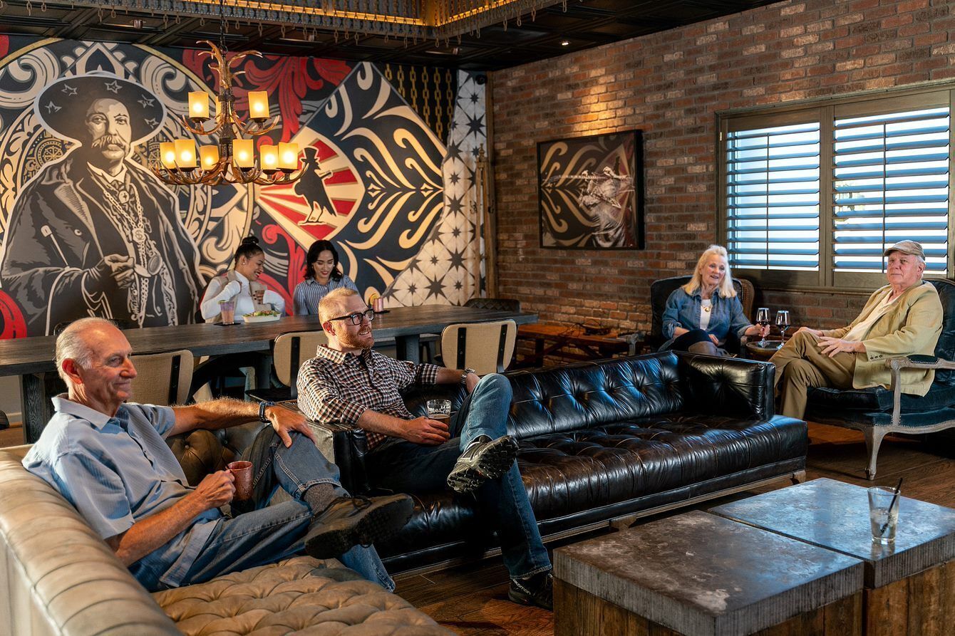 A cozy lounge area with leather sofas, a mural, and a brick wall.