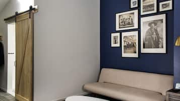 Un espace d’accueil doté d’une porte coulissante en bois, d’un canapé beige, d’une table basse blanche et d’un mur orné de photographies en noir et blanc encadrées.