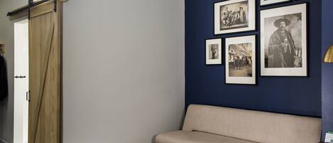 Zona de recepción con puerta corredera de madera, un sofá color beige, una mesa baja blanca y una pared decorada con fotografías blanco y negro enmarcadas.