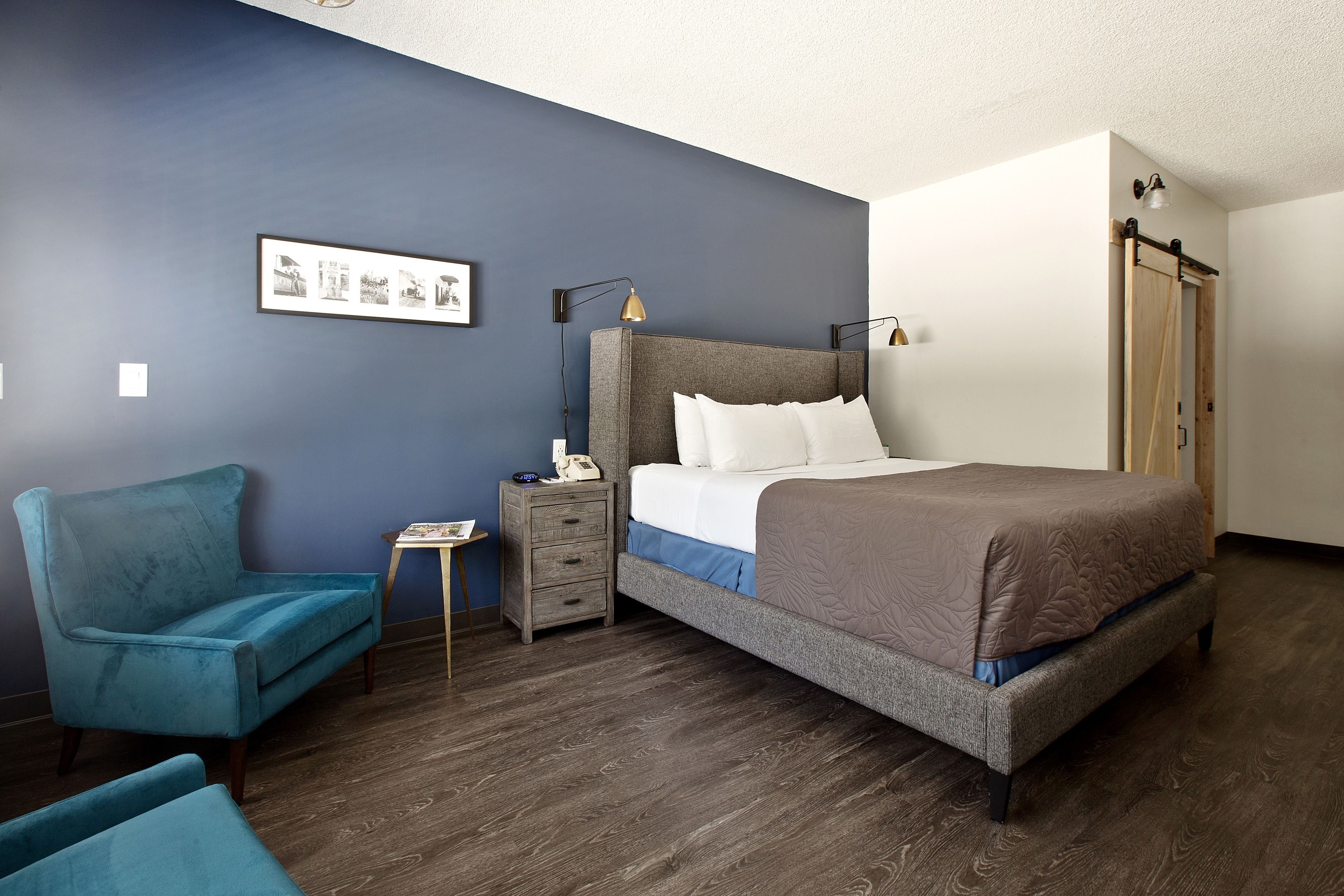 Ein Schlafzimmer mit Bett, Nachttisch, Sessel und Kleiderschrank.