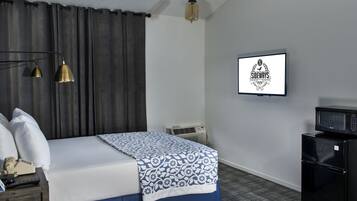Quarto de hotel com cama, luminária de cabeceira, ar condicionado e micro-ondas.