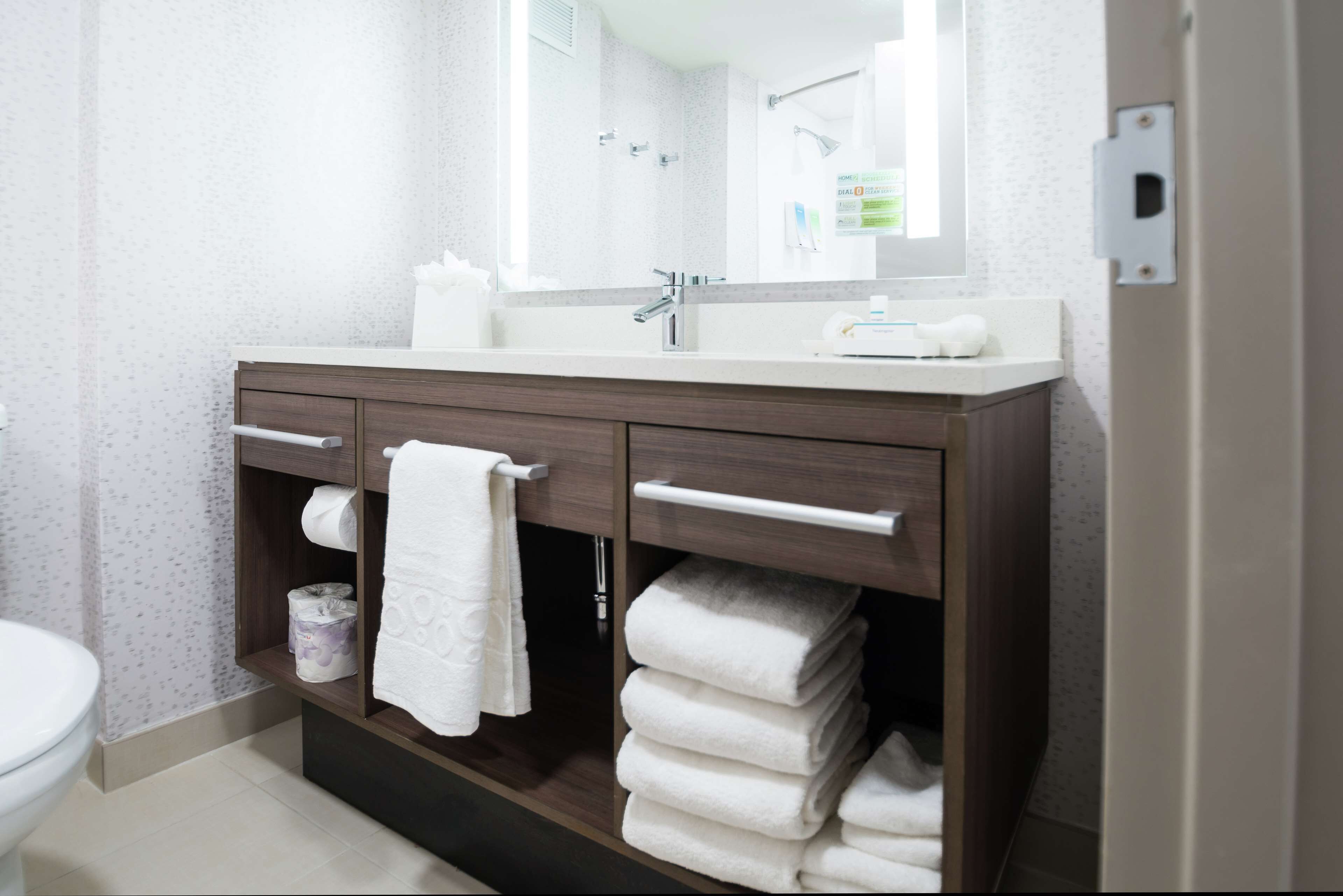 Un baño con lavamanos blanco, tocador de madera oscura y un espejo grande.