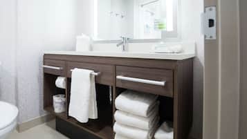 Un baño con lavamanos blanco, tocador de madera oscura y un espejo grande.