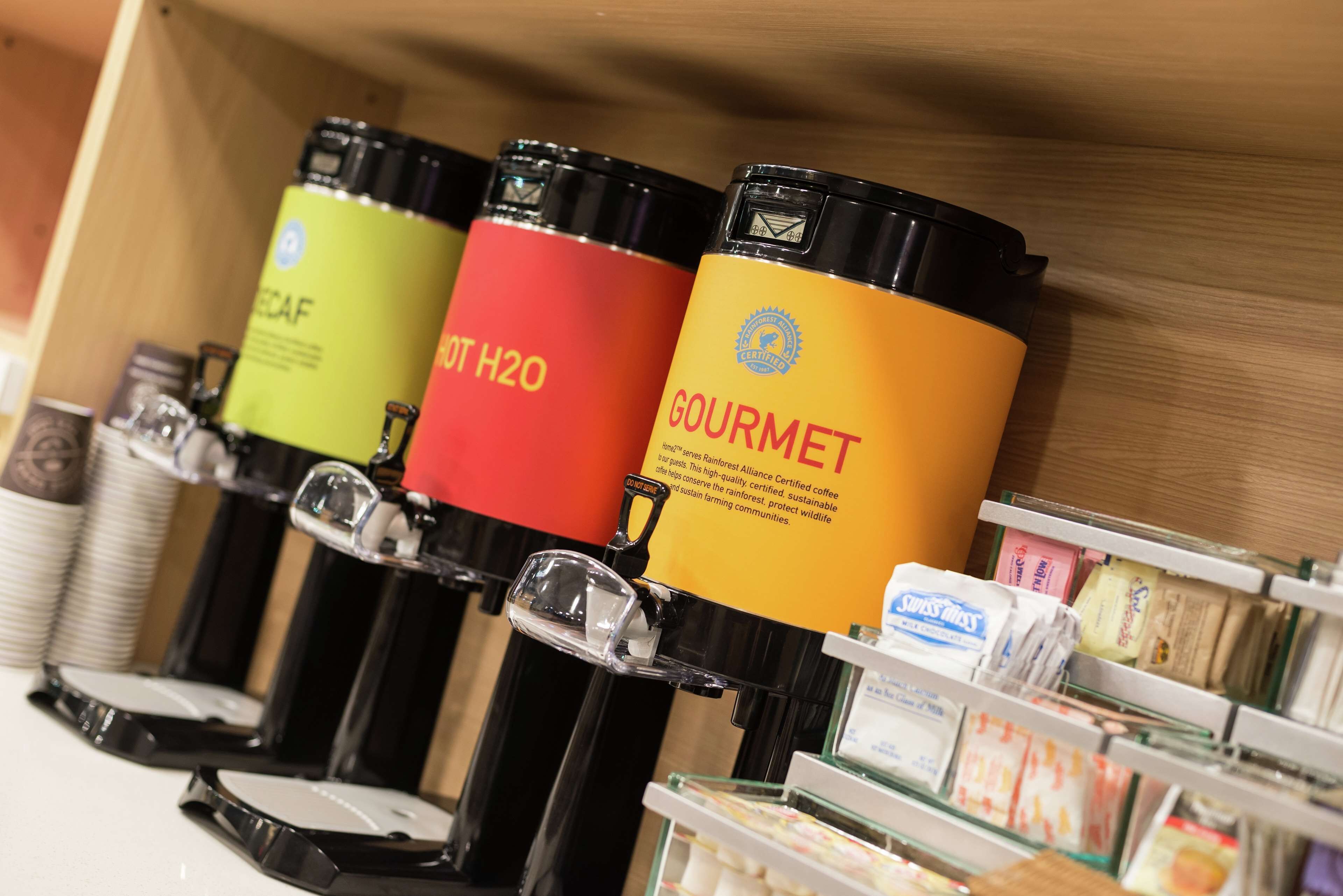 A coffee station with labeled dispensers for different types of coffee.