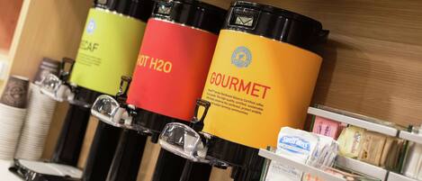 A coffee station with labeled dispensers for different types of coffee.