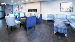 A modern lounge area with seating arrangements, a flat-screen TV, and artwork on the walls.