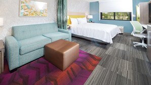 A hotel room with a bed, a sofa, a desk, and a chair.