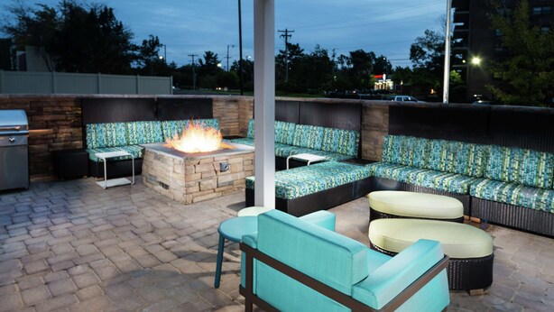 An outdoor patio with a fire pit, seating area, and a grill.