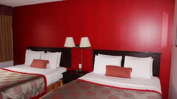 Une chambre d’hôtel avec deux lits, des murs rouges et une table de chevet avec des lampes.