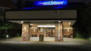Un hotel Howard Johnson con un cartel iluminado llamativo, un acceso cubierto y una fachada de piedra.