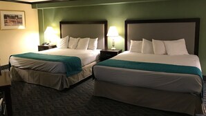 Habitación de hotel con dos camas, cada una con cabecera, mesitas de noche, lámparas y una alfombra verde.