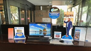 Una recepción de hotel con una computadora portátil, un premio 'Best Travel Rewards', un cartel de '¿Lo has visto?' y un letrero de 'Wyndham Rewards'.