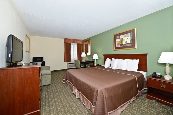 A hotel room with a large bed, a desk with a computer, a television, and a telephone.