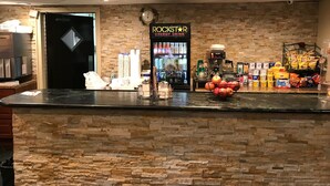 Una barra con dispensador de bebidas, aperitivos y un fondo de pared de piedra.