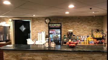 Een toonbank met een ROCKSTAR ENERGY DRINK automaat, een koffieapparaat en snacks.
