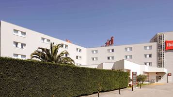 A modern hotel with a white facade, multiple windows, and a prominent red logo.