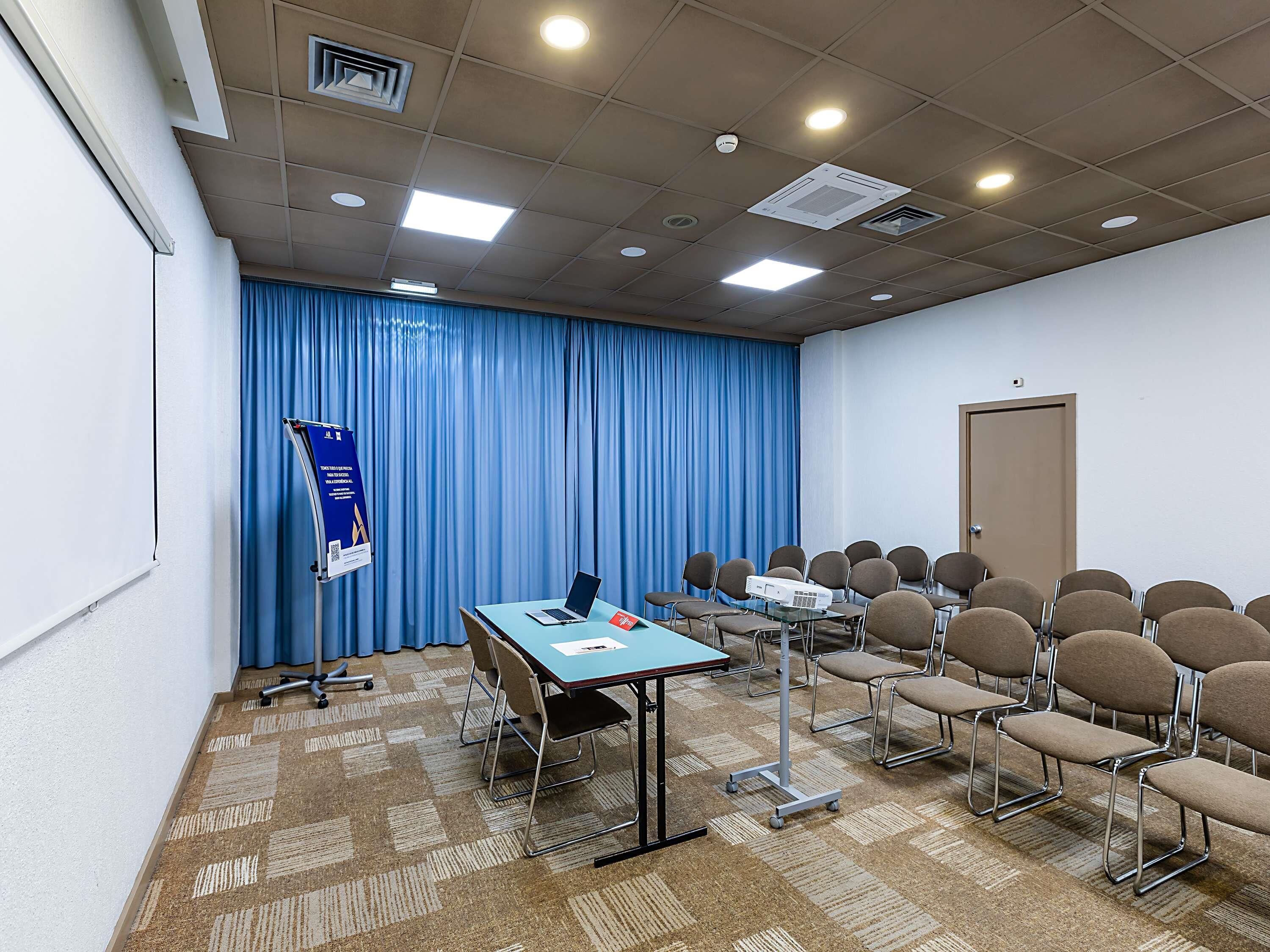 A conference room with a projector, laptop, and rows of chairs.