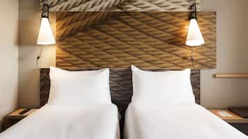 Habitación de hotel con dos camas, cabecera de madera e iluminación colgante.