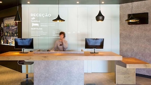 A reception desk with two monitors, a large information board, and pendant lighting. - ibis Porto Gaia (Vila Nova de Gaia)