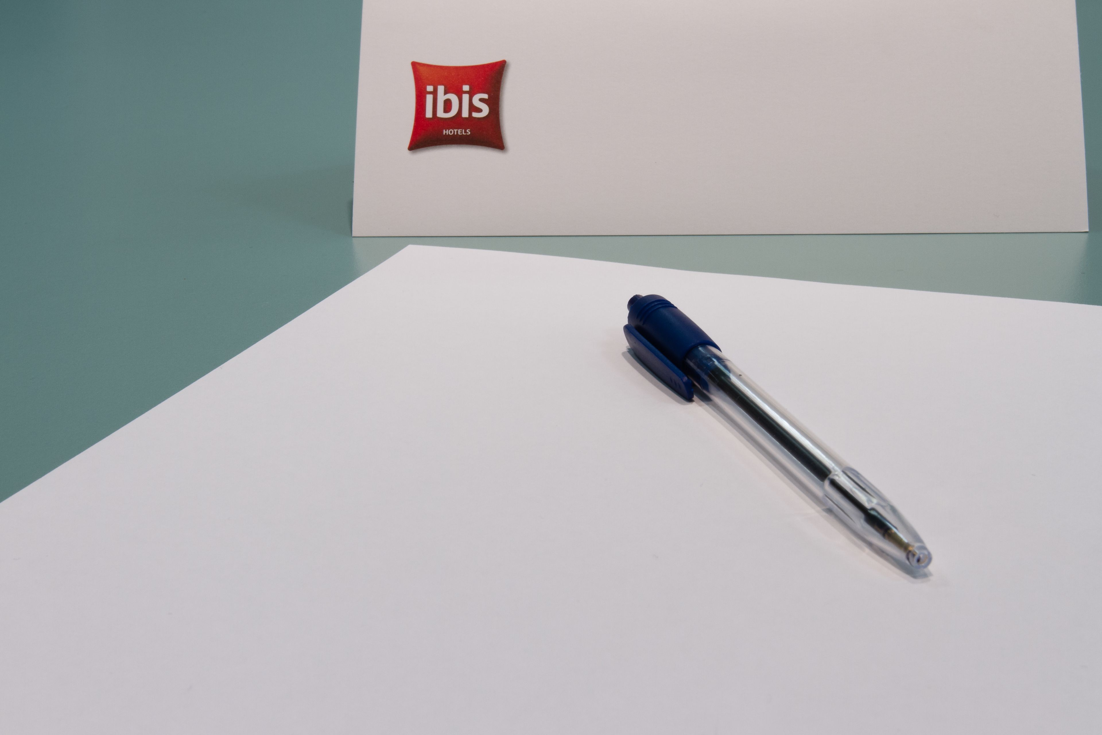 A pen on a white surface with a red logo in the background.
