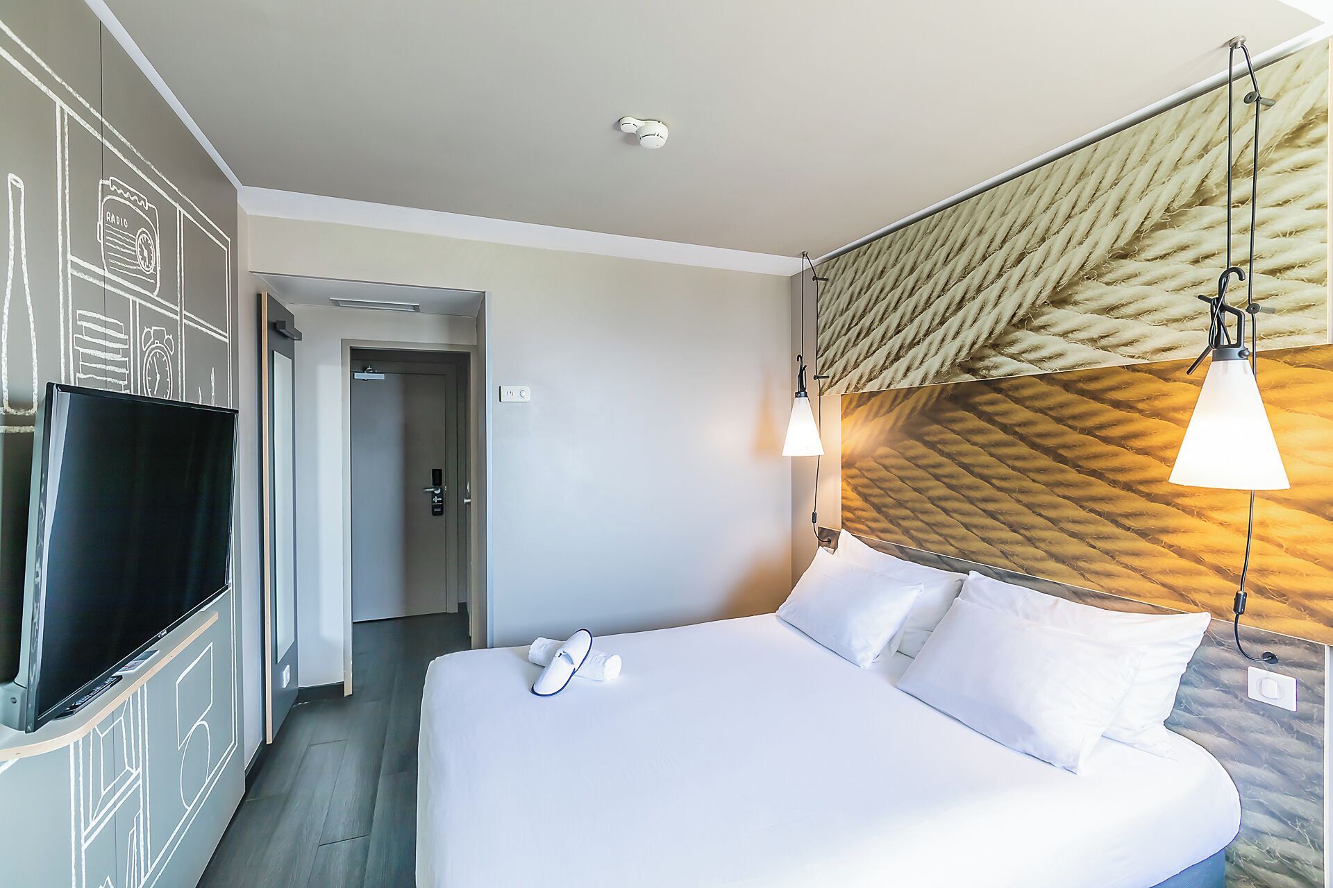 Hotelkamer met een bed, televisie, deur en een muur met een structuur.