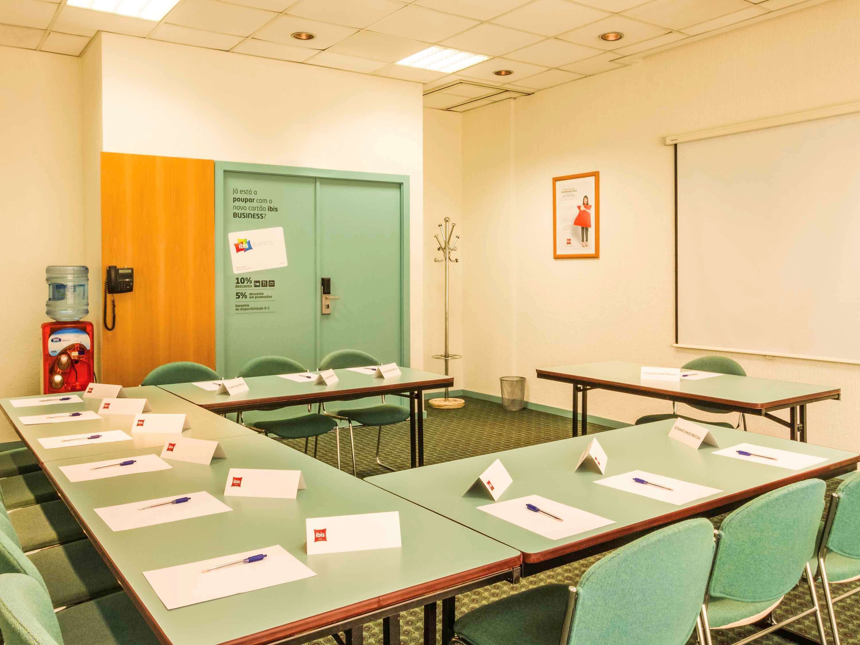 A conference room with green tables, name cards, and a water dispenser.
