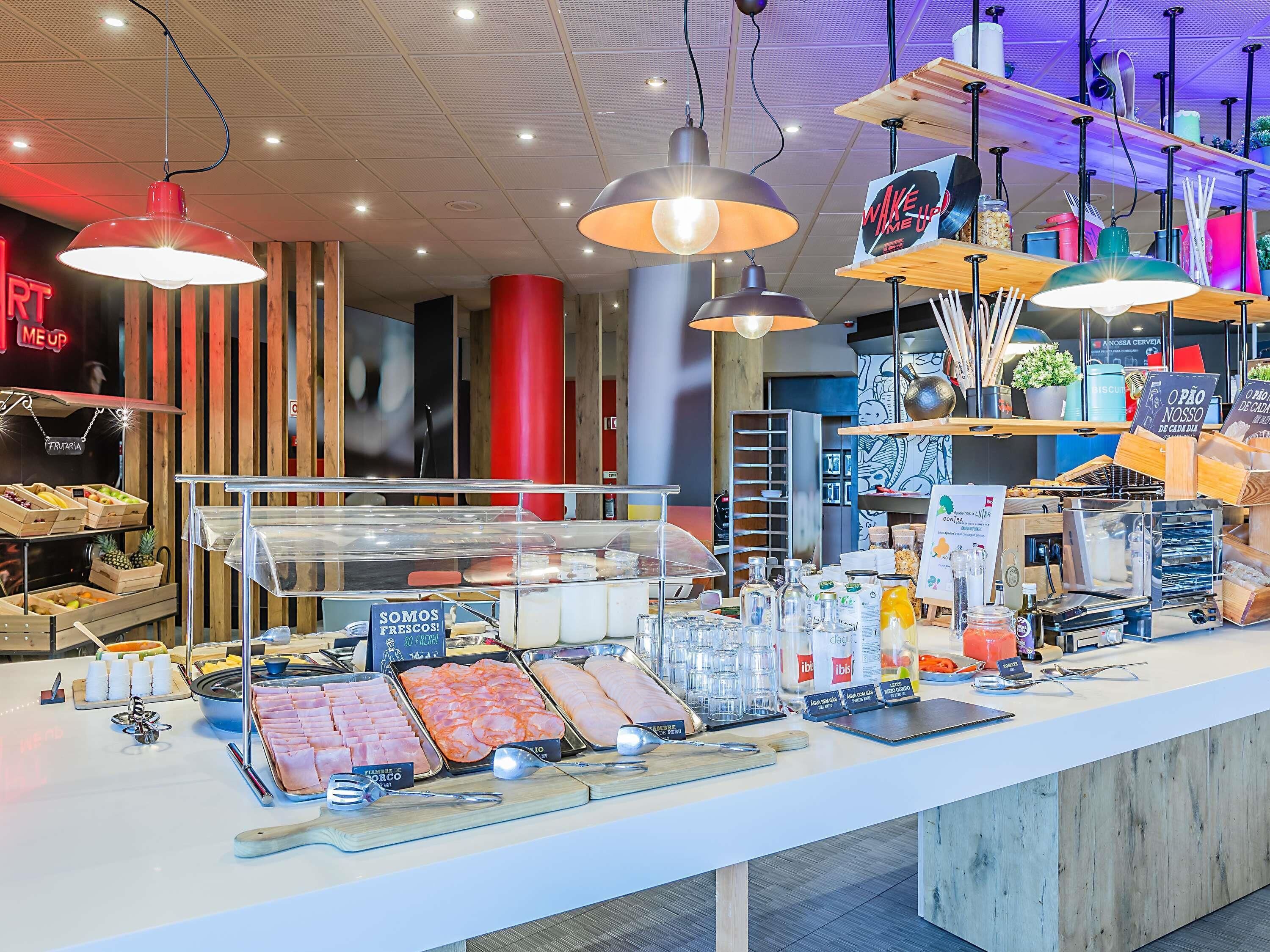 Una presentación de alimentos con diferentes carnes y quesos, una estación de café y un letrero que dice 'SOMOS FRESCOS!'.