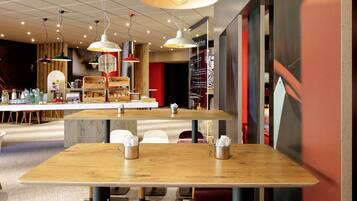A modern cafe with wooden tables and hanging pendant lights.