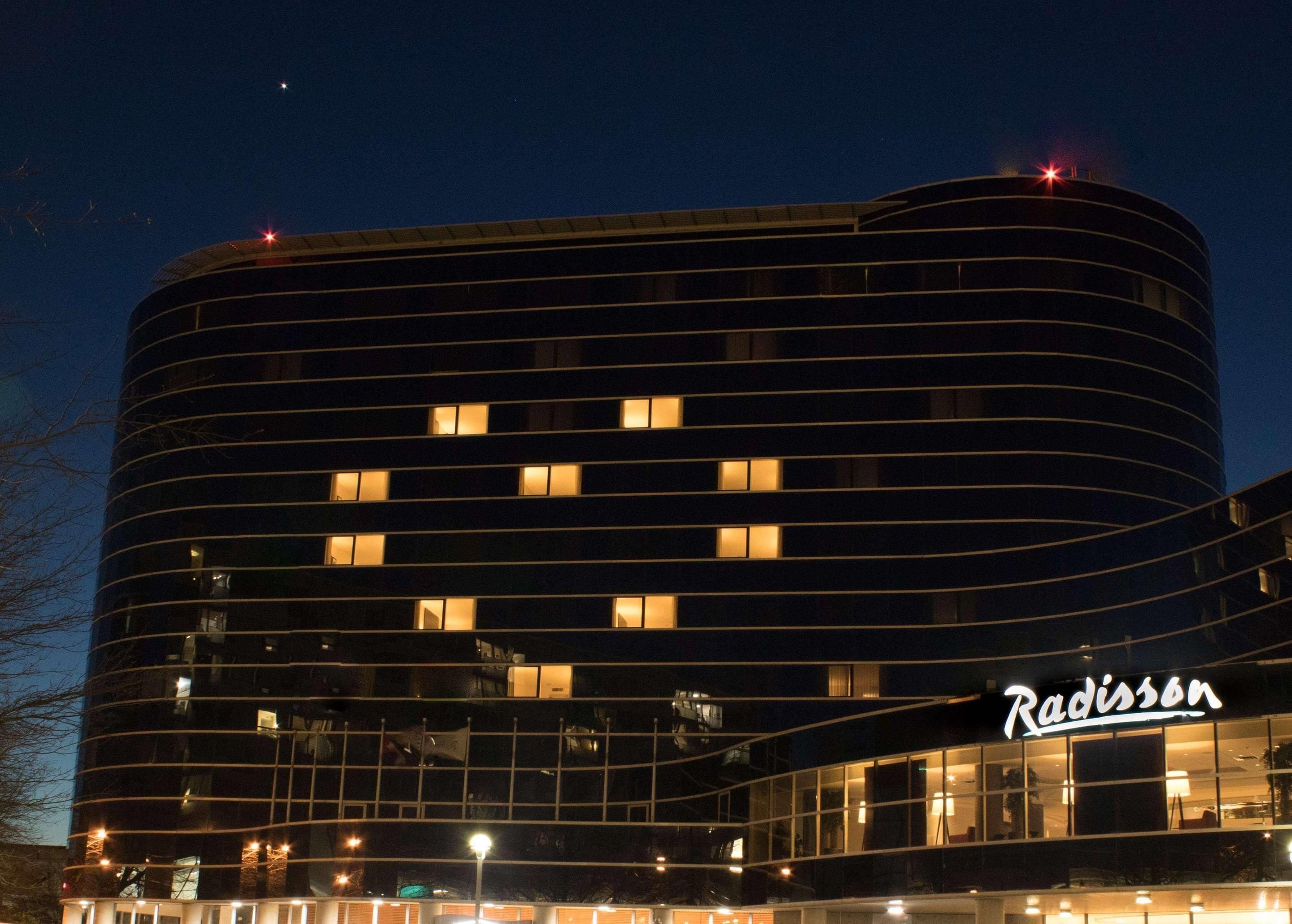 A modern hotel with a curved facade, multiple windows, and a prominent 'Radisson' sign.