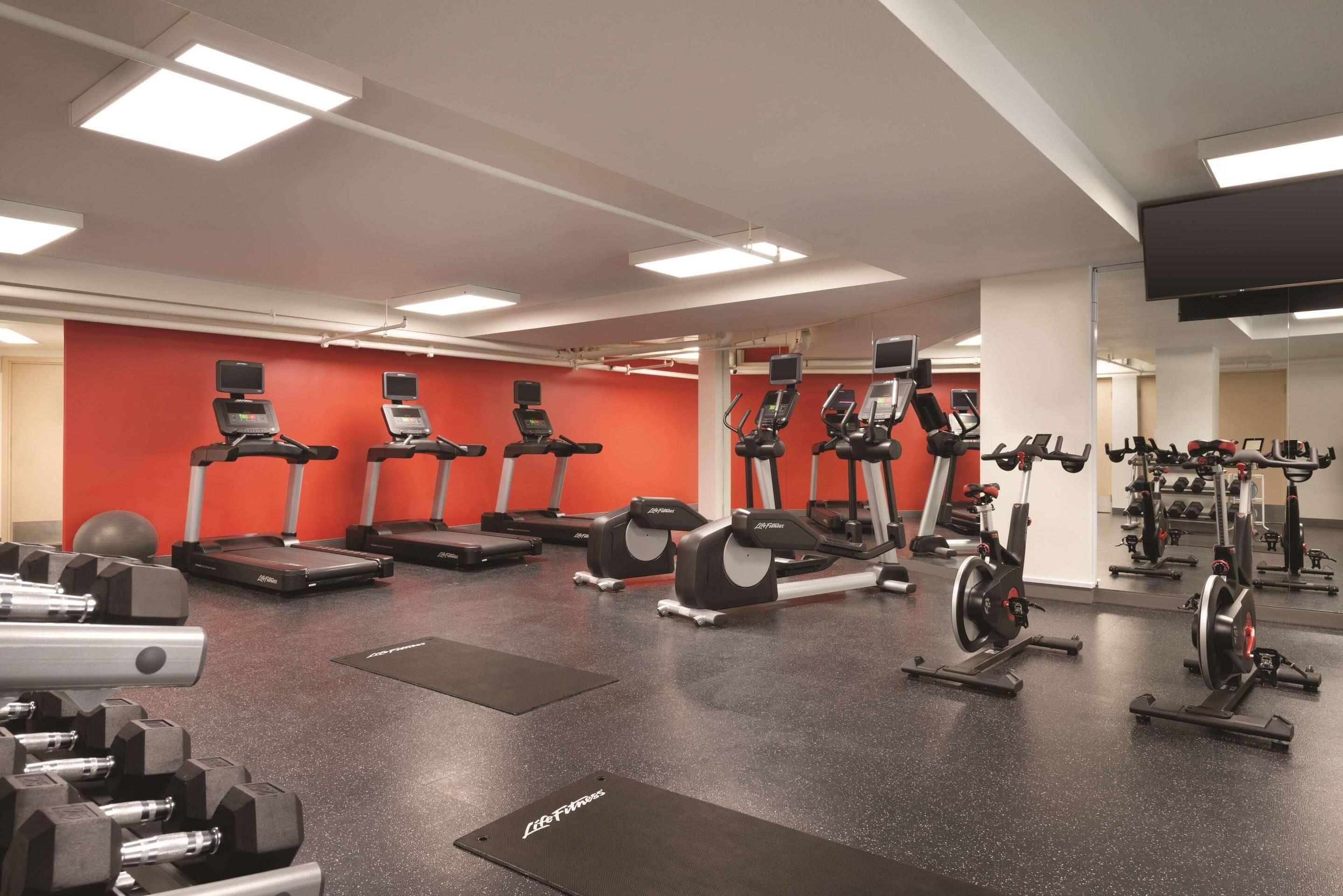 Une salle de sport équipée de tapis de course, de vélos elliptiques et de matériel de musculation.